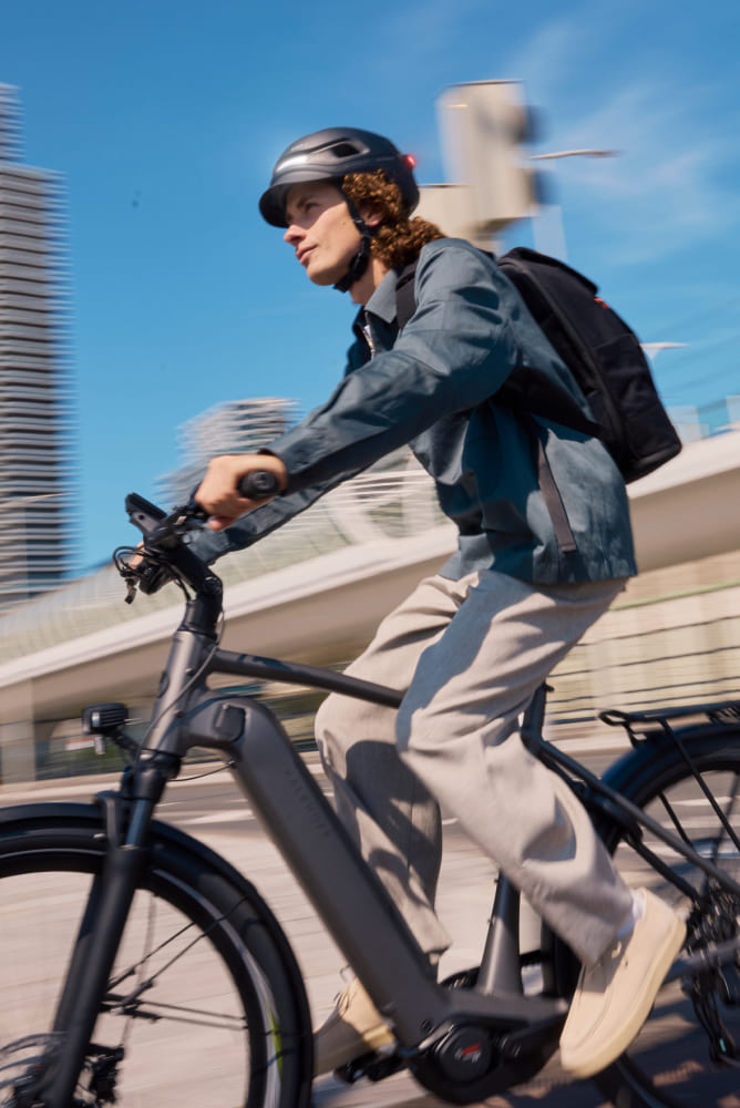 Un cycliste circulant en vélo électrique en ville, équipé d'un casque UNIT 1