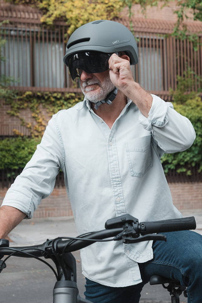 Un cycliste en train de régler la visière magnétique de son casque intelligent UNIT 1