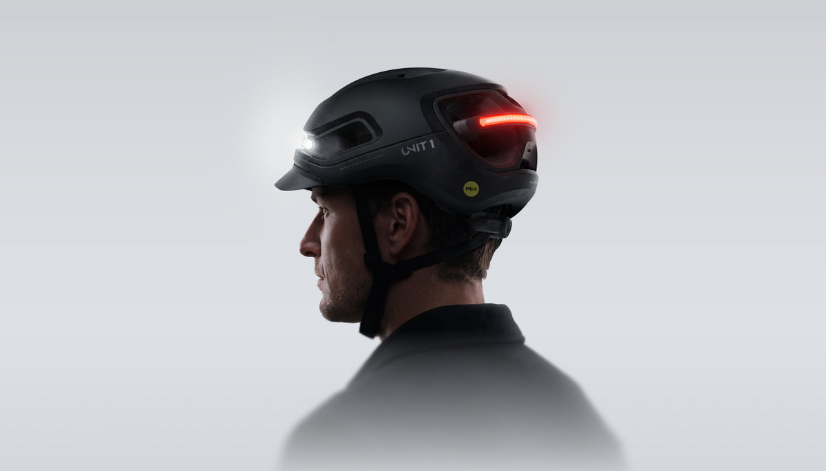 Radfahrer im Profil mit schwarzem UNIT 1 AURA Smart-Helm, Front- und Rücklicht leuchten