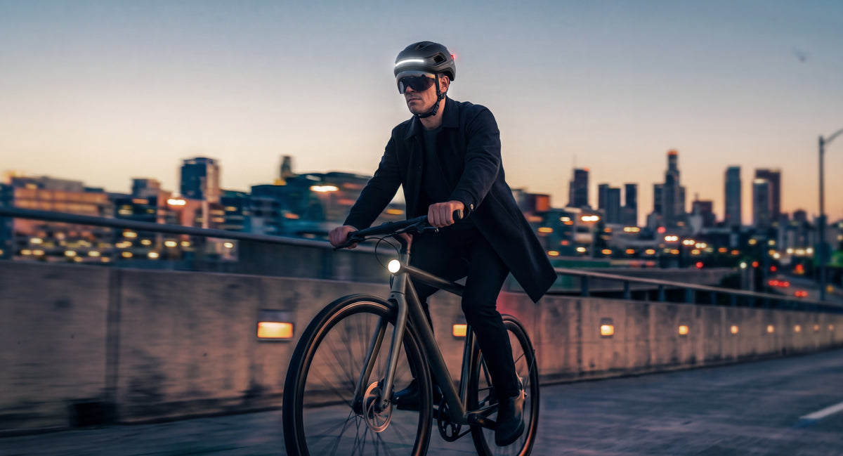 Rider wearing AURA MIPS with the city skyline at dusk