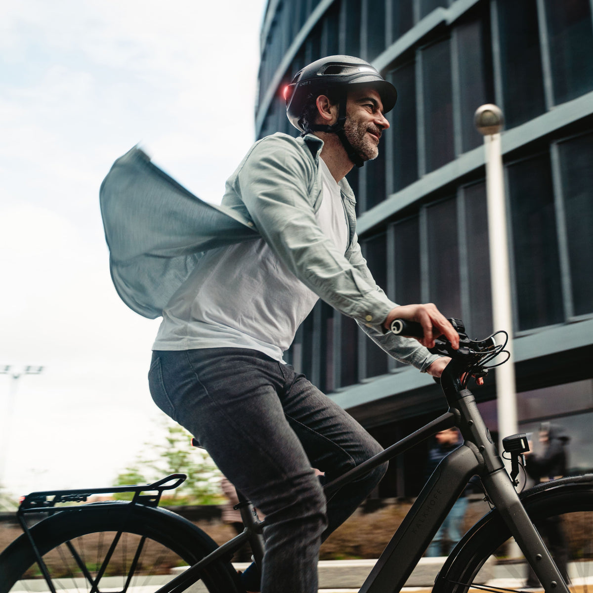 Cycliste urbain en vélo électrique dans la ville, portant un casque AURA noir