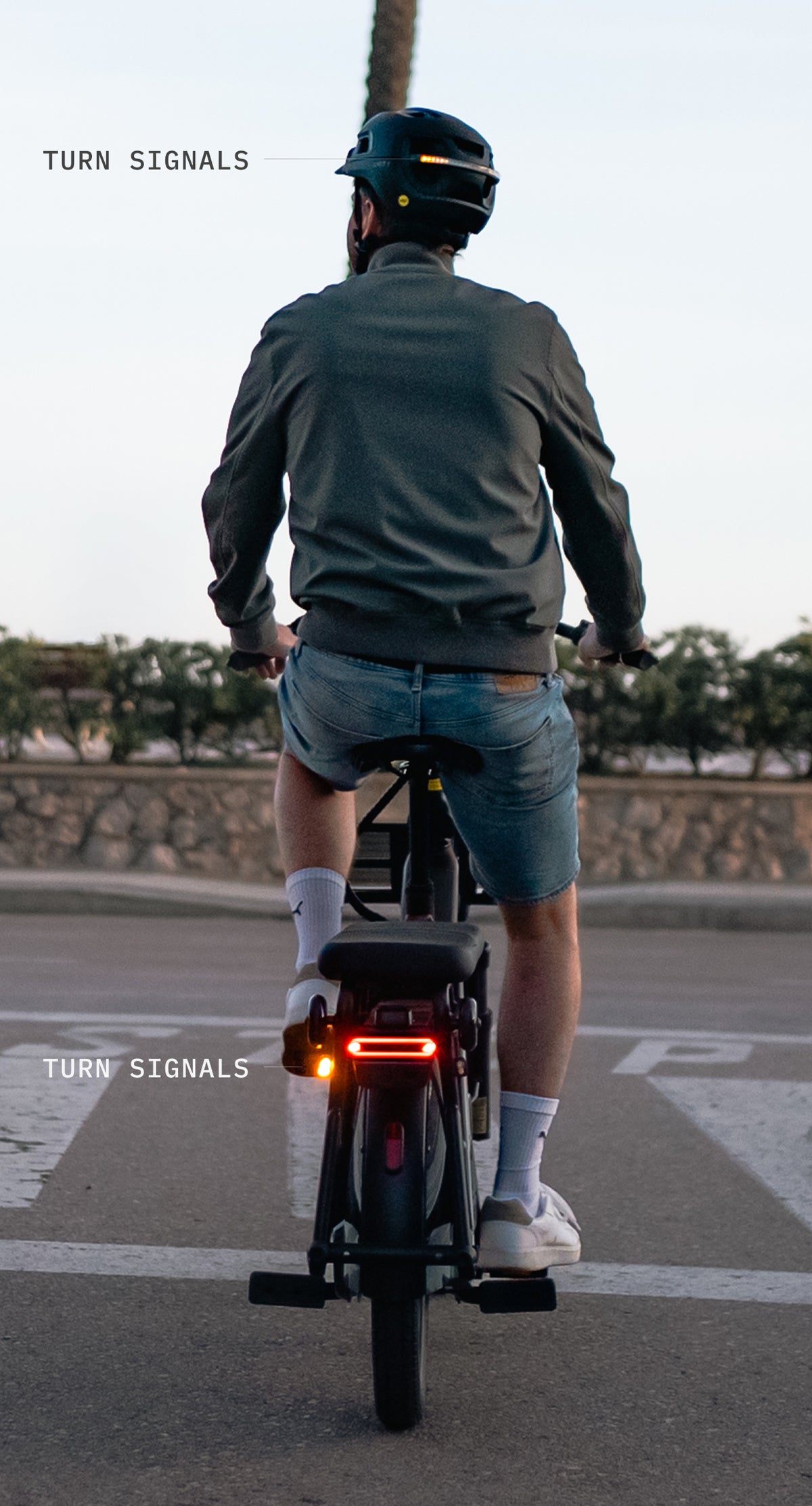 Rider on an e-bike seen from behind, with turn signals on the helmet and the bike